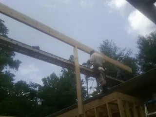 Carpenter setting a ridge beam over a new addition frame — Ice Dam Removal by Roofing Brothers in Humansville