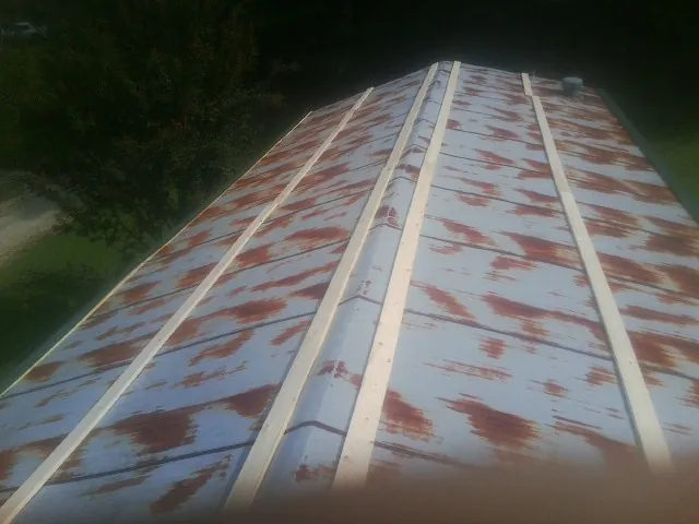 Rusted metal roof panels with new wood purlins before replacement — Storm Damage Roof Repair in Humansville by Roofing Brothers