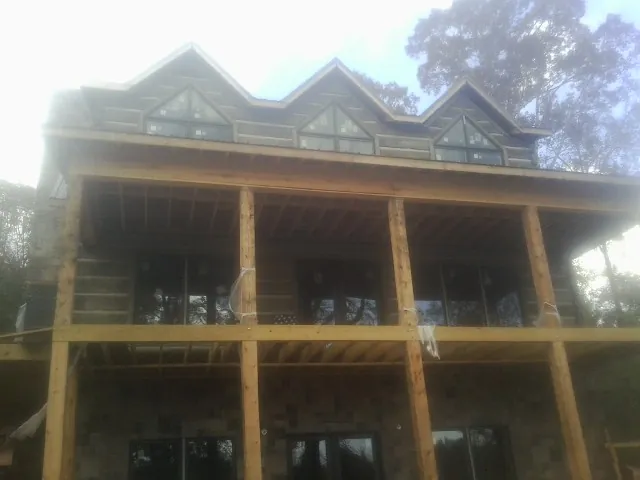 Dormers and porch framing on a large log home under construction — Roof Coating work by our crew in Humansville