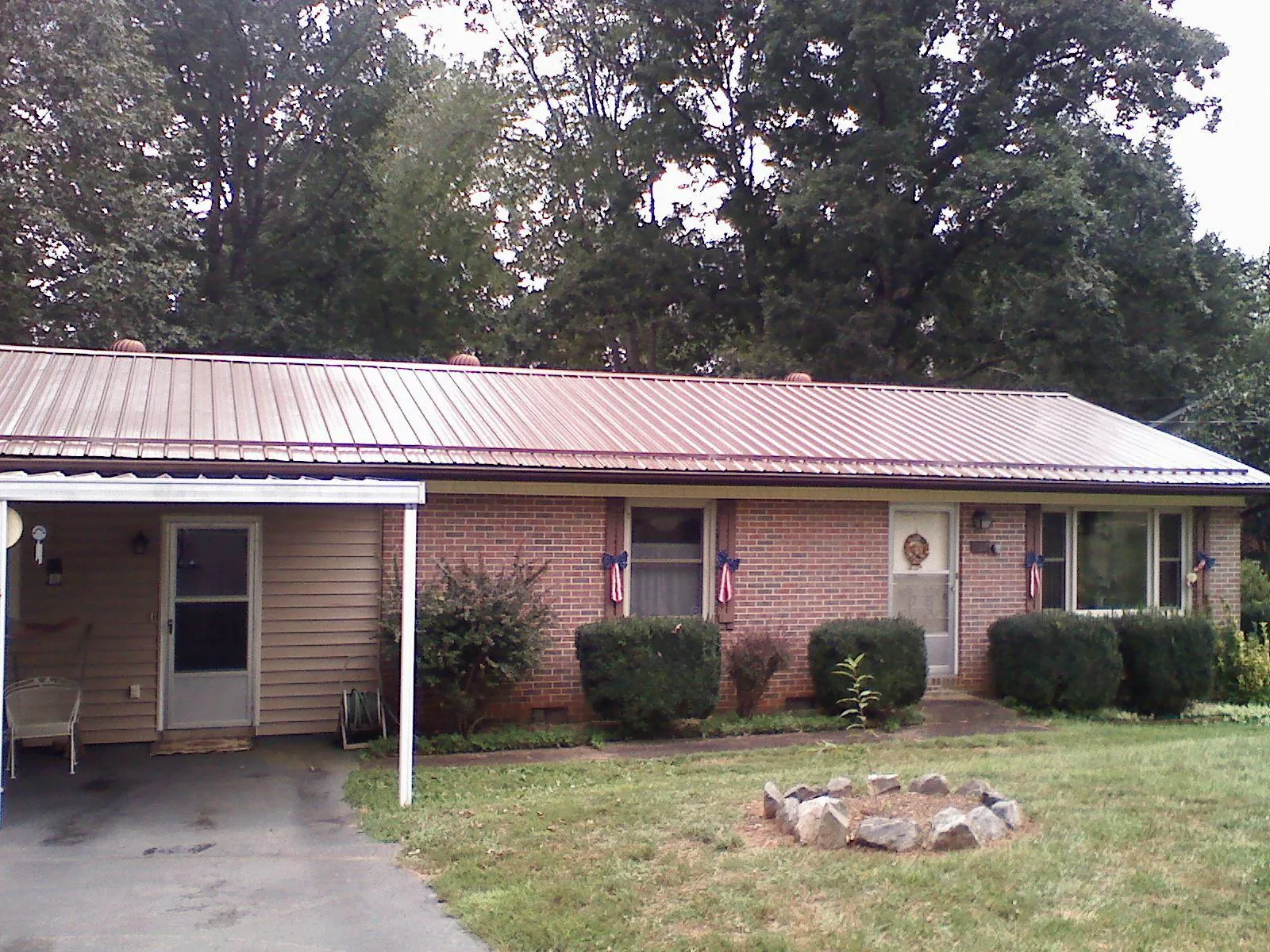 Bronze metal roof and carport on a brick ranch home — Roof Repair work by our crew in Humansville