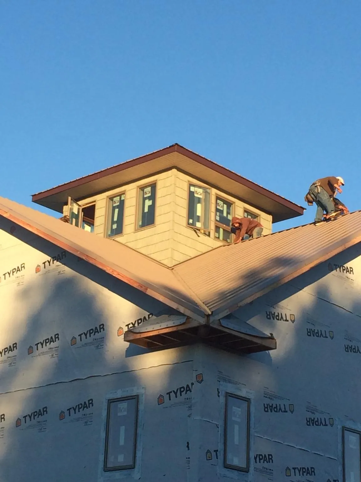 Roofers working around a rooftop cupola on a new metal roof at sunset — Roof Waterproofing in Humansville by Roofing Brothers